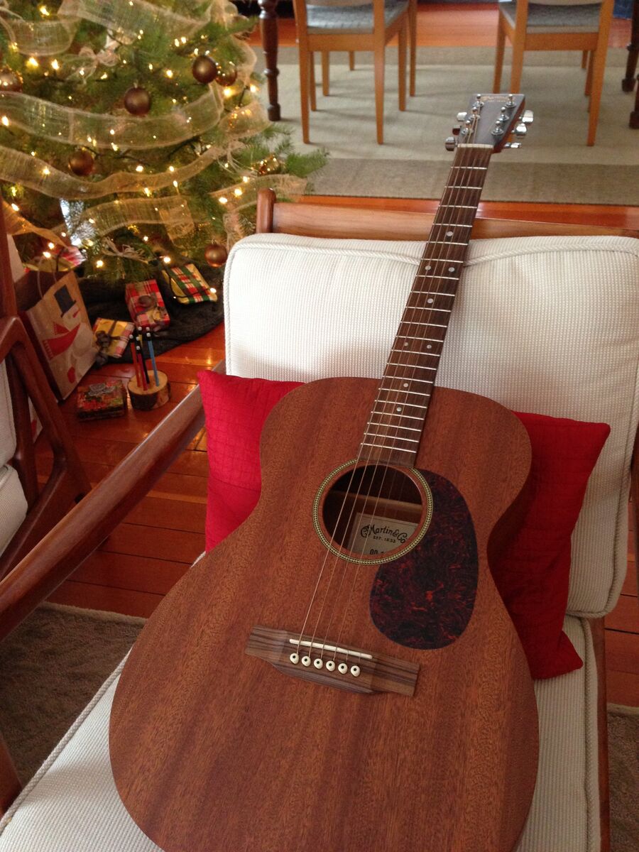 Martin acoustic guitar on a white chair beside a Christmas tree