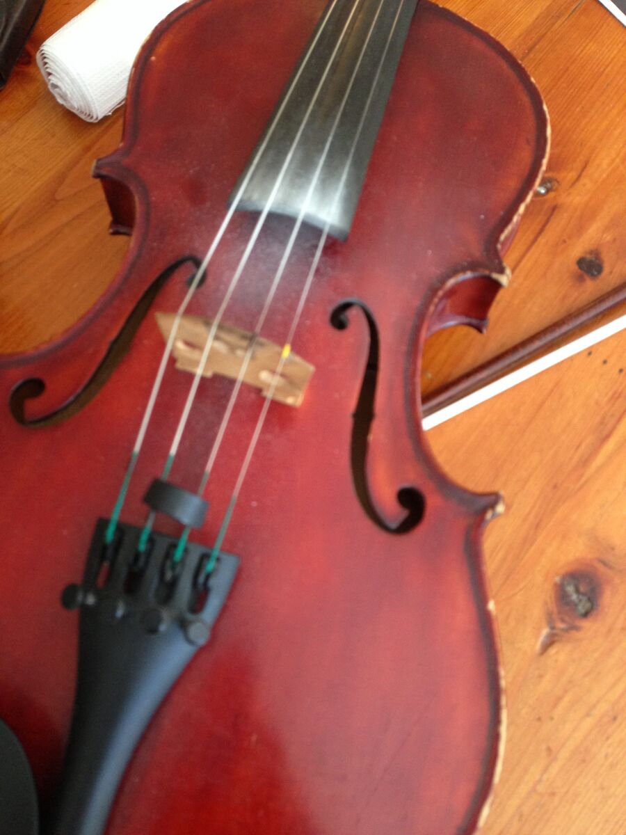 Red violin resting on a wooden table