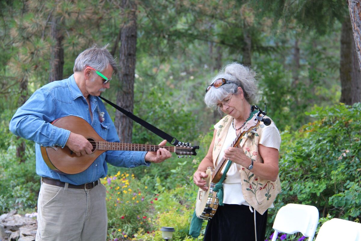 Two musicians playing mandolin and banjo in a garden